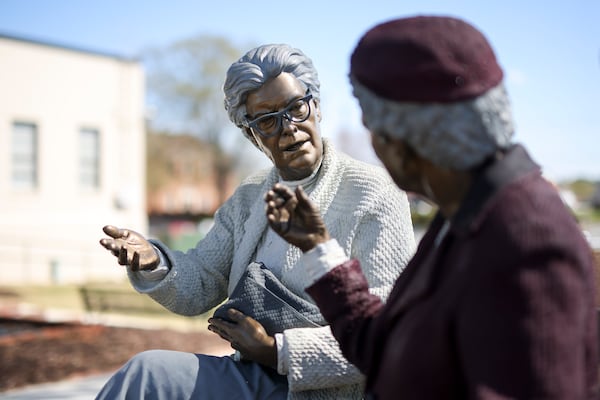 The life-size, realistic sculpture titled, “Crossing Paths,” by Seward Johnson is shown, Thursday, March, 20, 2025, in Monroe, Ga. There are 10 statues that can be seen playing chess on a side street, playing music on the corner of the town green, hailing a cab holding an umbrella or a police officer writing a ticket in front of a parking space, among others. The sculptures will be in downtown Monroe until February 2026. (Jason Getz / AJC)