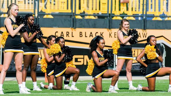 FILE - In this Sept. 30, 2017 photo, five Kennesaw State University cheerleaders take a knee during the national anthem prior to a college football game against North Greenville, in Kennesaw, Ga. Kennesaw State University's decision to remove its cheerleaders from the field after they protested police brutality during the national anthem has cost Georgia taxpayers $145,000 in a legal settlement. Former cheerleader Tommia Dean will get $93,000 of the award, with the rest going to her attorneys. The Marietta Daily Journal obtained a copy of the settlement Wednesday, Dec. 4, 2019, through an Open Records Act request.