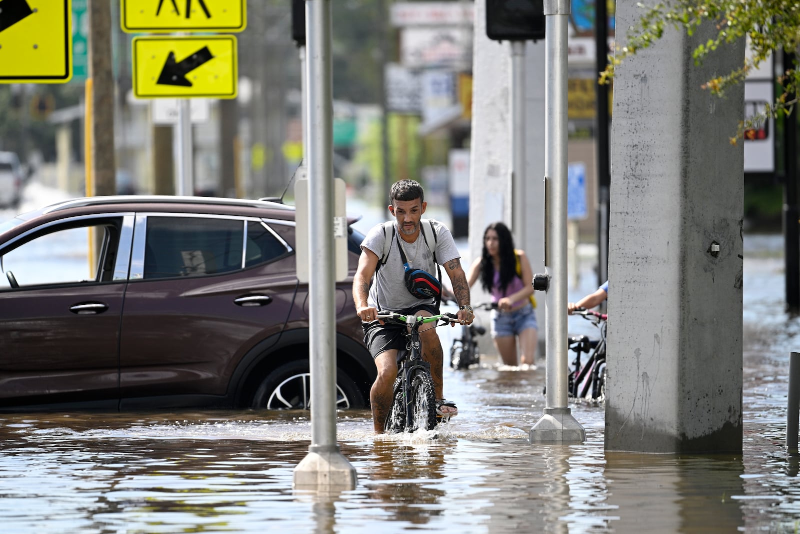 FILE - Mica Martell, left, and his niece and nephews ride bicycles through a flooded neighborhood, Sept. 27, 2024, in Crystal River, Fla. (AP Photo/Phelan M. Ebenhack, File)