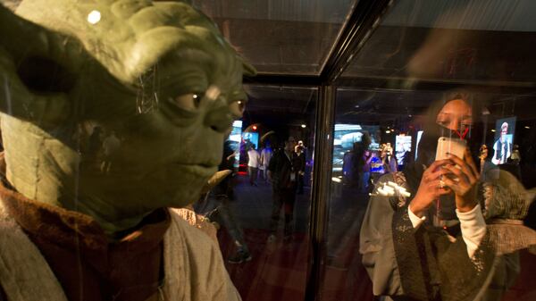 FILE - In this Friday, Feb. 17, 2017, file photo, a visitor films at the Star Wars exhibition, an American epic space franchise, centered on a film series, during the Saudi Comic Con (SCC) which is the first event of its kind to be held in Jiddah, Saudi Arabia. The kingdom, which bans movie theaters and other entertainment venues, is challenging its ultraconservative image and loosening the reins on fun by opening its doors to live shows, including some American ones. (AP Photo, File)