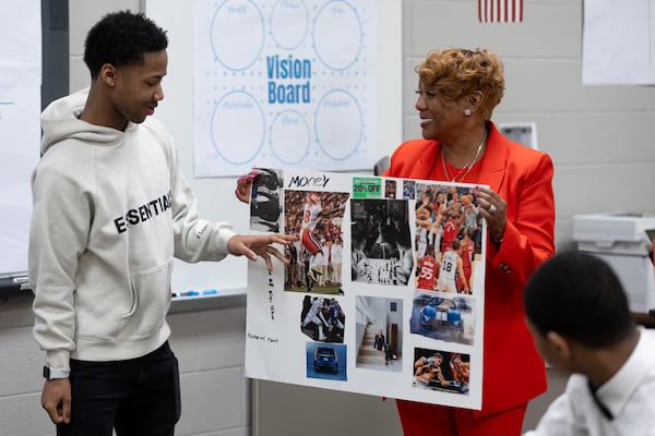 Redan High School FACE advocate Melinda Adams holds Montravious Favors' vision board during a class presentation following an end-of-year group project in Stone Mountain on Tuesday, May 14, 2024. The DeKalb County School District has placed one-on-one mentors at some schools this year to help improve students' attendance, behavior and academic performance. (Steve Schaefer / AJC)