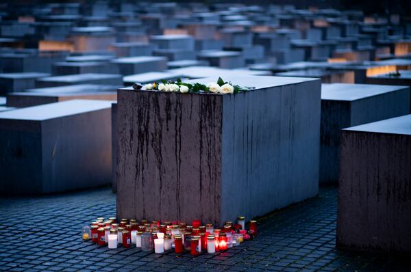 Candles and flowers are placed by a concrete slabs on the occasion of the International Holocaust Remembrance Day, marking the liberation of the Nazi death camp Auschwitz - Birkenau, at the Holocaust Memorial in Berlin, Germany, Monday, Jan. 27, 2025. (AP Photo/Markus Schreiber)