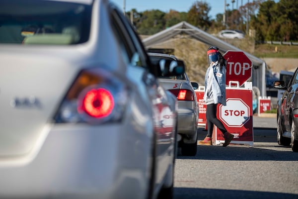 Workers walked up and down a line of cars to gather personal information before COVID-19 testing at a DeKalb County Department of Health COVID-19 drive-thru testing site in Doraville. (Alyssa Pointer / Alyssa.Pointer@ajc.com)