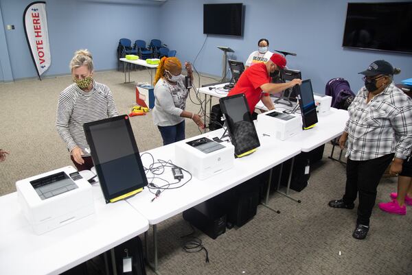  Poll workers unpack voting machines while setting up the Briarlake Baptist Church polling center in preparation for the election Tuesday.  STEVE SCHAEFER / SPECIAL TO THE AJC 