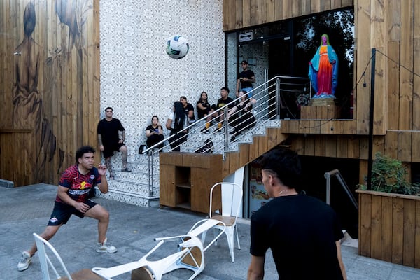 Workers at a bar play with a soccer ball outside their workspace during a power outage in Santiago, Chile, Tuesday, Feb. 25, 2025. (AP Photo/Matias Basualdo)