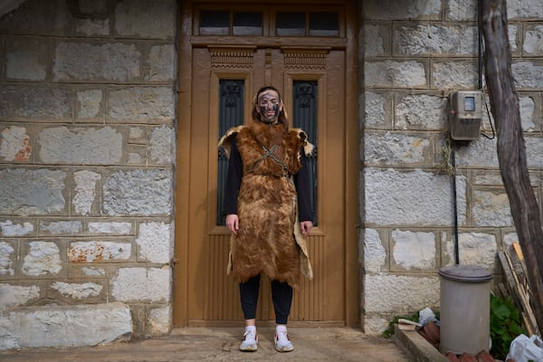 Asimina Philipou, 16 ,poses for a portrait, dressed in animal skins and heavy bronze bells, as part of carnival celebrations in Distomo, a village in central Greece, on Monday, March 3, 2025. (AP Photo/Petros Giannakouris)