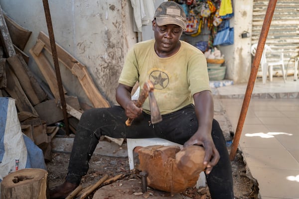 Woodcarver Papis Kanté sculpts a wooden hippopotamus to be exhibited in the "Rebondir" exhibition as part of the Dakar 2024 Biennial Off in Dakar, Senegal, Thursday, Nov. 28, 2024. (AP Photo/Sylvain Cherkaoui)