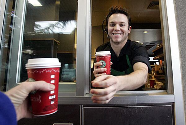 Starbucks barista Brian Sayer hands coffee drinks out the store drivethru window and to a motorist, Dec. 1, 2005, in Parkland, Wash.