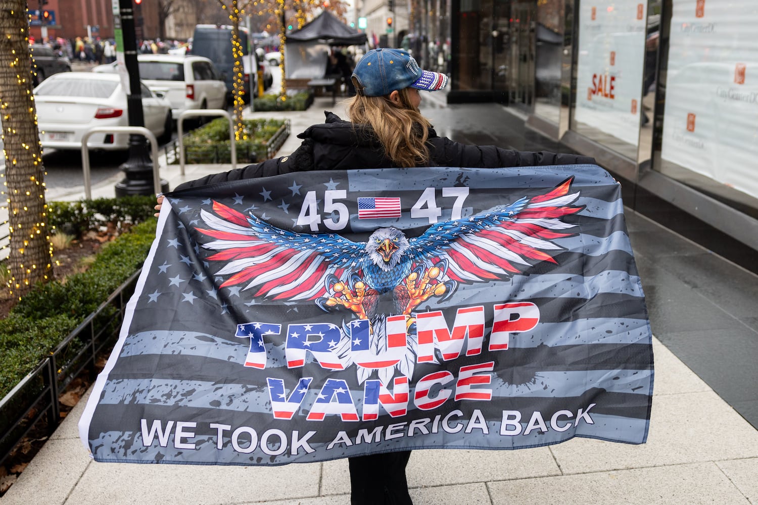 Ashleigh Jorajuria of Georgia poses with a Trump flag while walking toward a Trump rally at Capital One Arena in Washington, D.C. on Sunday, January 19, 2025, one day before Donald Trump’s inauguration. (Arvin Temkar / AJC)