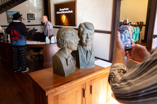 A visitor takes a picture of a bust of Rosalyn and Jimmy Carter in Plains. (Arvin Temkar/AJC)