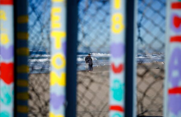 Two people embrace on the U.S. side of the border, seen through the border wall Monday, Jan. 7, 2019, seen from along the beach in Tijuana, Mexico. U.S. Vice President Mike Pence said Monday the White House is looking into the legality of declaring a national emergency to circumvent Congress and begin construction on President Donald Trump's long-promised Southern border wall. (AP Photo/Gregory Bull)