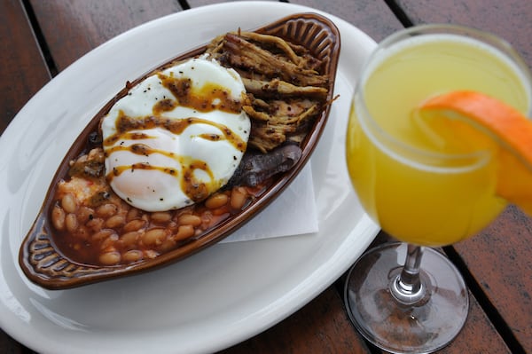 From the brunch menu at Arcadia in Little Five Points, The Rustler is pimento cheese grits topped with pulled pork, caramelized red onion, baked beans, house-made Carolina barbecue sauce and a fried egg, pictured here with a mimosa. CONTRIBUTED BY BECKYSTEIN.COM