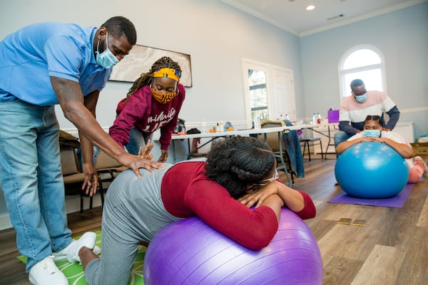 Birth by Grace Midwifery holds a class where Parish Munroe (left) is shown massage techniques by Christine Taylor on mother-to-be Kiah Munroe in Peachtree City on Saturday, Jan. 23, 2021. The families are planning home births under the guidance of Taylor, a certified nurse-midwife, and doula Dawn Hutcherson.  (Jenni Girtman for The Atlanta Journal-Constitution)