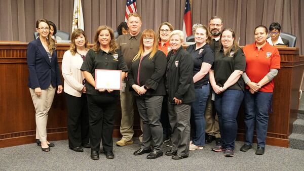 Cobb County 911 operator Dana Bell (third from left) was recently recognized by county leaders for answering more than 20,000 calls in less than a year, breaking the county's record for most calls handled. Bell is surrounded by Cobb County Commissioner Keli Gambrill (left), Cobb's Emergency communications director Melissa Alterio (second from left) and several fellow county dispatchers.