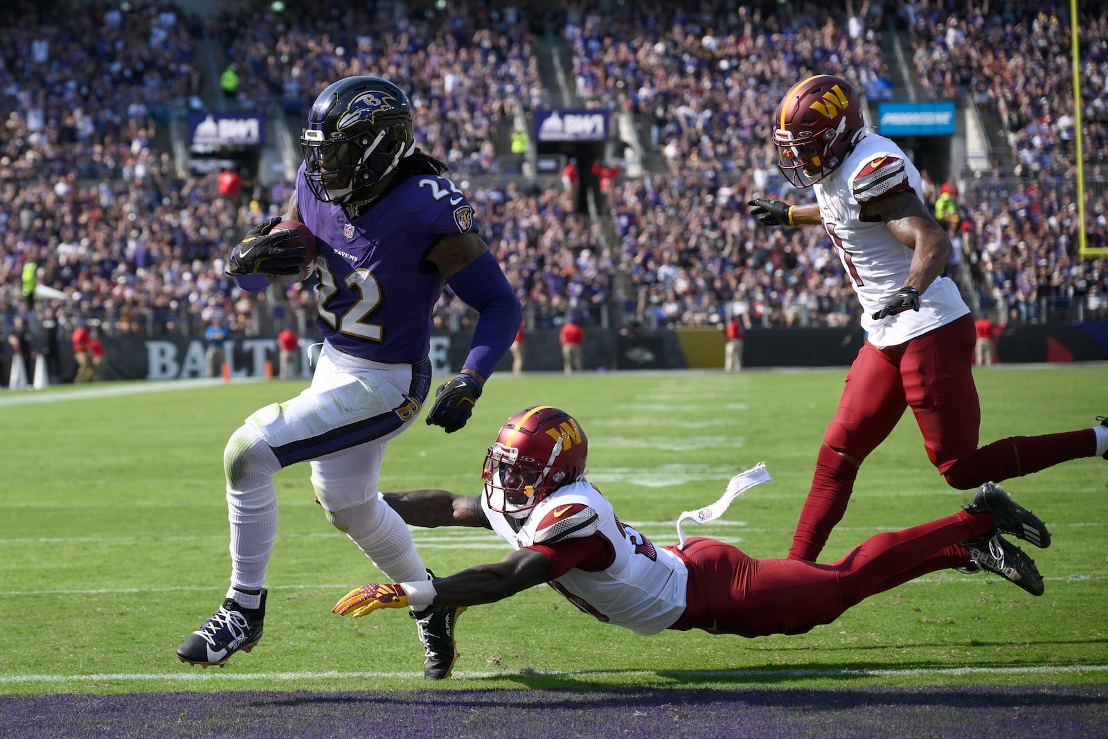 Baltimore Ravens running back Derrick Henry (22) scores past Washington Commanders safety Quan Martin and safety Jeremy Chinn, right, during the first half of an NFL football game Sunday, Oct. 13, 2024, in Baltimore. (AP Photo/Nick Wass)