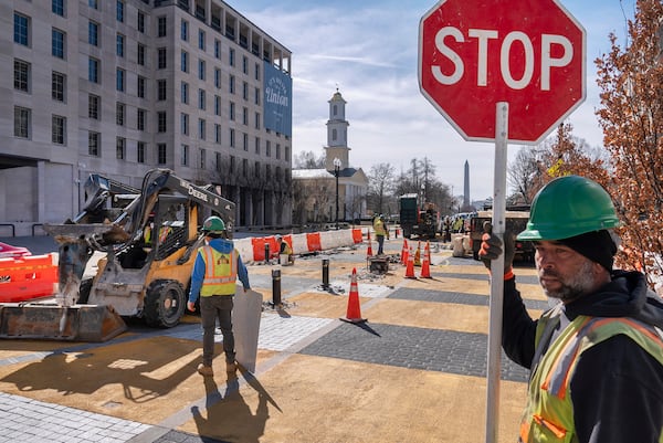 With the White House and Washington Monument in the background, a worker holds a traffic stop sign as demolition begins on the Black Lives Matter mural, Monday, March 10, 2025, in Washington. (AP Photo/Jacquelyn Martin)