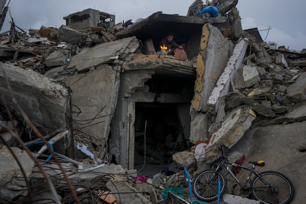 Mohammad Naser, sits by a fire as he takes cover from the rain under the destruction of his house caused by the Israeli air and ground offensive in Jabaliya, Gaza Strip, Thursday, Feb. 6, 2025. (AP Photo/Abdel Kareem Hana)