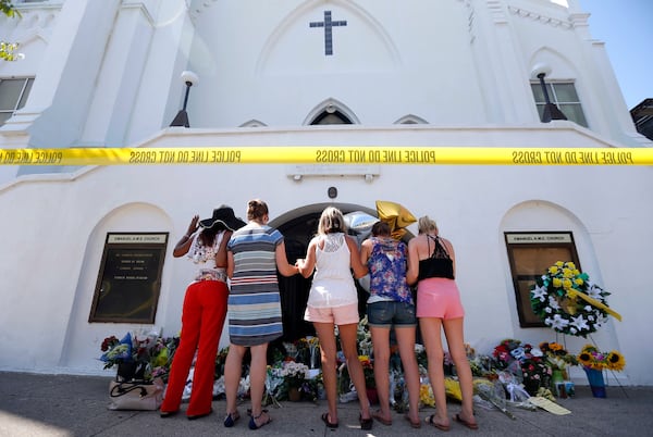 FILE - In this June 18, 2015, file photo, a group of women pray at a makeshift memorial on the sidewalk in front of the Emanuel AME Church in Charleston, S.C. One big change happened in conservative South Carolina after a racist gunman killed nine black people during a Bible study five years ago, the Confederate flag came down. But since then, hundreds of other monuments and buildings named for Civil War figures, virulent racists and even a gynecologist who did painful, disfiguring medical experiments on African American women remain.