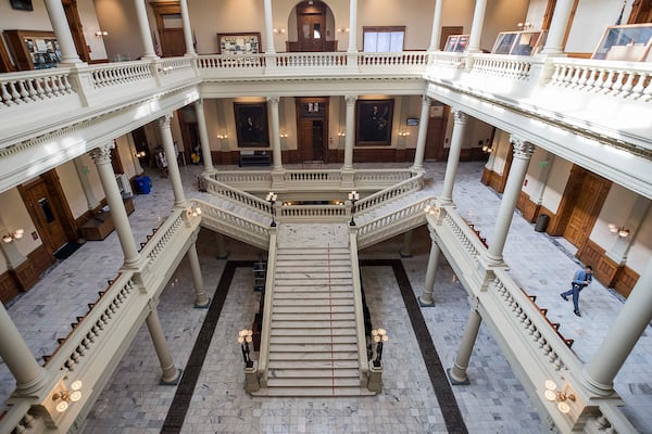 A Georgia state trooper, right, walks the empty hallways of the Georgia Capitol on Friday during the 29th day of the state’s legislative session. Out of caution and in relation to the coronavirus, the General General Assembly suspended the legislative session until further notice. (ALYSSA POINTER/ALYSSA.POINTER@AJC.COM)