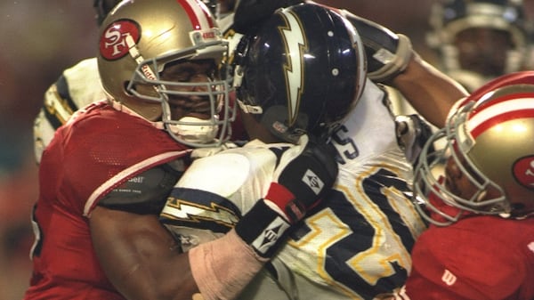 Chargers running back Natrone Means is tackled by several San Francisco 49ers players during Super Bowl XXIX .