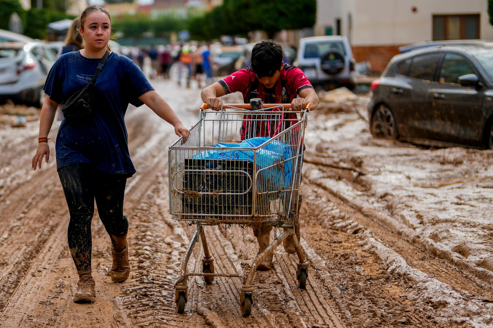 Two people push a cart loaded with belongings in Valencia, Spain, Thursday, Oct. 31, 2024. (AP Photo/Manu Fernandez)