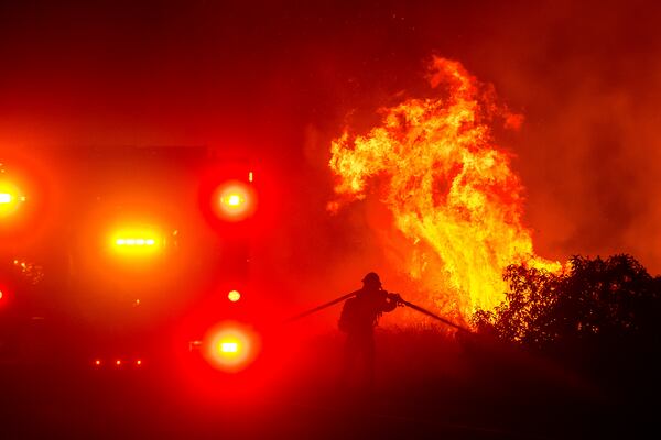 A firefighter sprays water while battling the Lilac Fire near the Bonsall community of San Diego County, Calif., on Tuesday, Jan. 21, 2025. (AP Photo/Noah Berger)