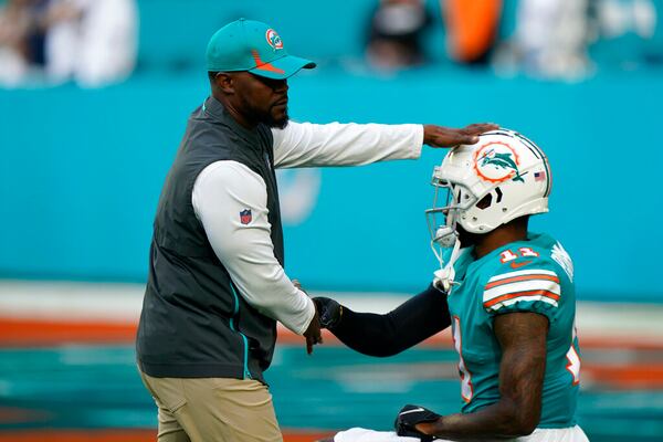 Miami Dolphins head coach Brian Flores pats the helmet of Miami  wide receiver DeVante Parker (11) as he stretches during warm-ups ahead of an NFL football game against the New England Patriots, Sunday, Jan. 9, 2022, in Miami Gardens, Fla. (AP Photo/Wilfredo Lee)