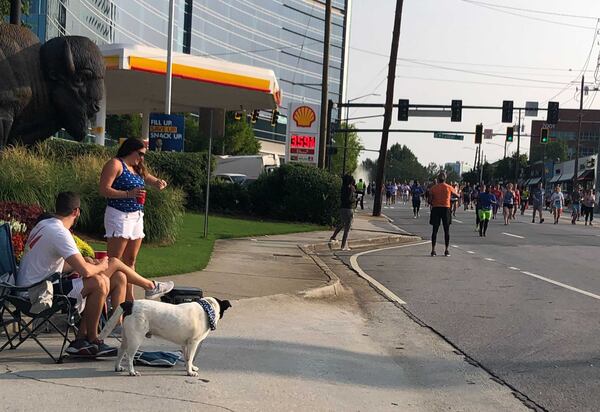 Friends Blair Reynolds, 36, of Smyrna and Carla, 35, and Mitchell Finch, 34, of Vinings and their dog Bruce watch the race from the top of Cardiac Hill. (Photo: Lizzie Kane/AJC)