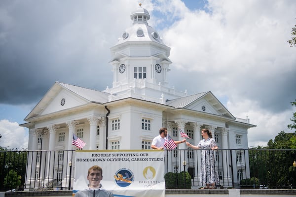 Main Street Manager of City of Moultrie Bolt VanDalsem and Executive Director of Moultrie Convention and Visitor Bureau Caroline Barber zip tie American flags on a Carson Tyler poster in front of Colquitt County Courthouse in Moultrie on Wednesday, July 24, 2024.  (Ziyu Julian Zhu / AJC)