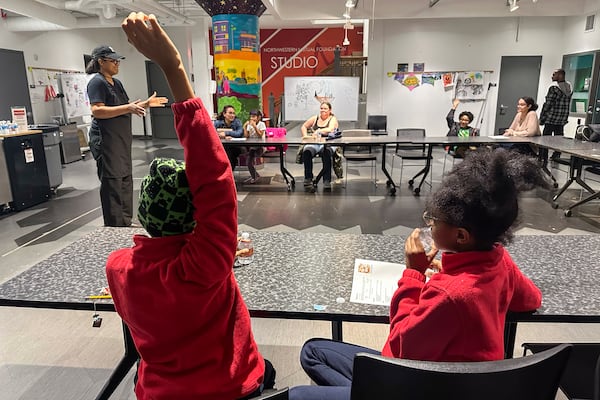 A child raises his hand to answer a question asked by Chef Sharrie Agee at the Milwaukee Public Library’s Snack Hack program for kids on Nov. 19, 2024, Milwaukee. (AP Photo/Devi Shastri)