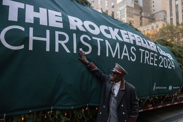 A man touches the Rockefeller Center Christmas tree at Rockefeller Plaza, Saturday, Nov. 9, 2024, in New York. (AP Photo/Yuki Iwamura)