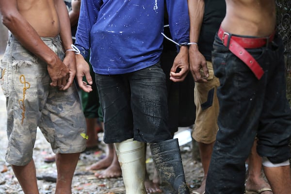 FILE- Filipino men have plastic zip ties on their wrists following a police raid at an alleged drug den as part of the continuing "War on Drugs" campaign of Philippine President Rodrigo Duterte near the Payatas dumpsite in suburban Quezon city, north of Manila, Philippines, Wednesday, Oct. 5, 2016. (AP Photo/Aaron Favila, File)