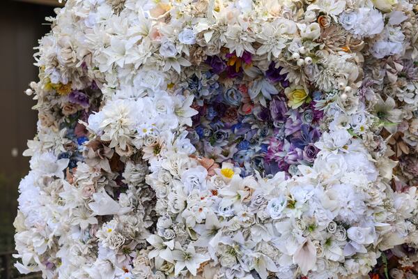 The artificial flowers that encompass this massive skull that sits along the Eastside Beltline Trail in Atlanta were collected from cemeteries across Georgia as part of an art installation titled "Steered by Falling Stars" created by Lamar Dodd School of Art Director Joseph Peragine and Professor of Art Mary Hallam Pearse. (Jason Getz / AJC)

