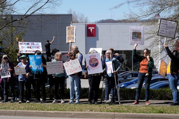 Protesters carrying signs and chant slogans against Elon Musk and President Donald Trump outside a Tesla dealership Saturday, March 22, 2025, in Franklin, Tenn. (AP Photo/George Walker IV)