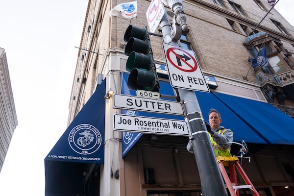 An SFMTA worker installs the Joe Rosenthal Way street sign to honor Rosenthal, who won the Pulitzer Prize for his iconic photo of U.S. Marines raising the flag on the Japanese island of Iwo Jima during WWII, Thursday, Dec. 12, 2024, in San Francisco. (AP Photo/Minh Connors)