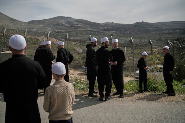 Druze men and boys stand near the border, as they wait for buses carrying members of the Syrian Druze community to cross from Syria in the village of Majdal Shams, located in the Israeli-controlled Golan Heights, Friday, March 14, 2025. (AP Photo/Leo Correa)