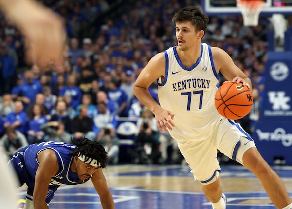 Kentucky's Kerr Kriisa (77) drives while Georgia State's Malachi Brown, left, loses his footing during the first half of an NCAA college basketball game in Lexington, Ky., Friday, Nov. 29, 2024. (AP Photo/James Crisp)