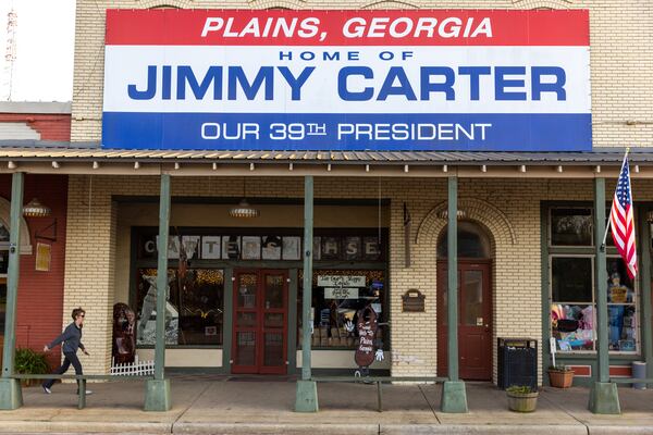 A person walks pasts stores on Main Street in Plains on Sunday, February 19, 2023. (Arvin Temkar / arvin.temkar@ajc.com)