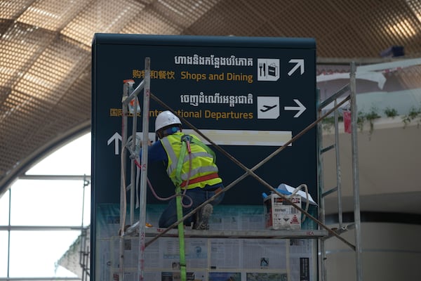 A worker paint a sign inside an under construction of a new airport of Techo International Airport at the outskirts of Phnom Penh Cambodia, Friday, March 21, 2025. (AP Photo/Heng Sinith)