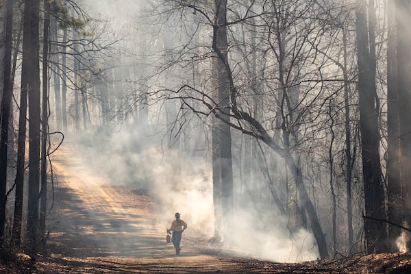 Emily Rapach, a wildlife biologist with the Georgia Department of Natural Resources, walks down Macedonia Cemetery Road in the Allatoona Wildlife Management Area while helping with a controlled burn of 237 acres Thursday, Jan. 16, 2025.   Ben Gray for the Atlanta Journal-Constitution