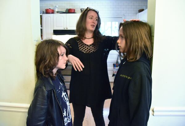 Snyder takes her 11-year-old son Mose’s height as his brother Lewis (left), 10 looks on at their home in Ormewood Park in 2017. HYOSUB SHIN / HSHIN@AJC.COM