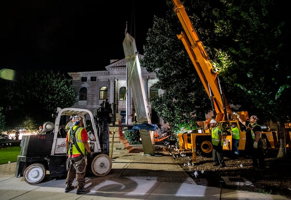 Workers remove a Confederate monument with a crane Thursday, June 18, 2020, in Decatur, Ga. The 30-foot obelisk in Decatur Square, erected by the United Daughters of the Confederacy in 1908, was ordered by a judge to be removed and placed into storage indefinitely. (AP Photo/Ron Harris)