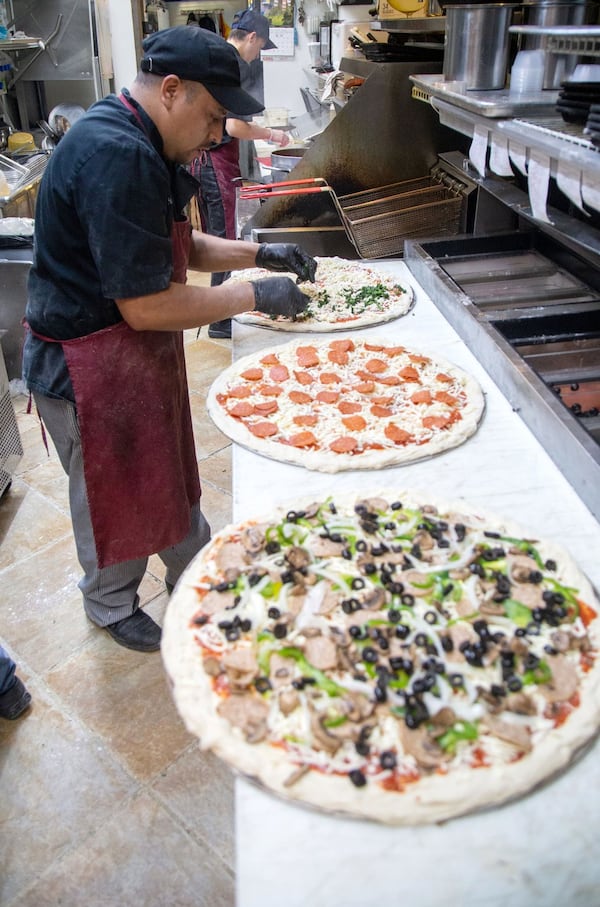 Felix Acosta makes pizzas during the Friday night rush at Fini’s Pizzeria in Lawrenceville. STEVE SCHAEFER / SPECIAL TO THE AJC