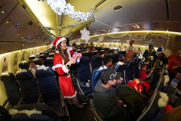 Flight attendant Kaori Kiguradze welcomes participants during the United Airlines annual "fantasy flight" to a fictional North Pole at Denver International Airport, Saturday, Dec. 14, 2024, in Denver. (AP Photo/David Zalubowski)