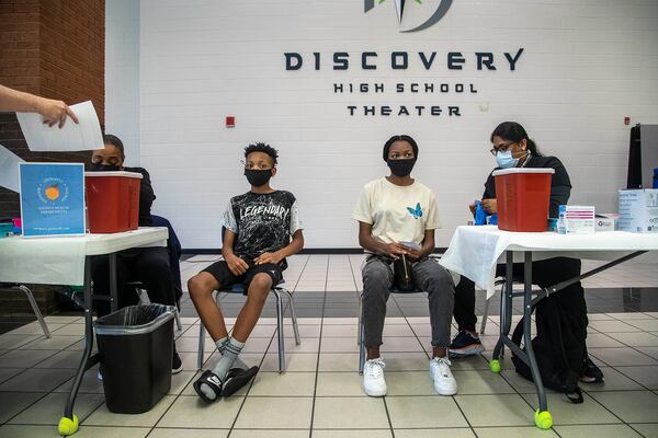 Siblings Jared McCauley, 14, second from left, and Maya McCauley, 15, second from right, wait to receive the Pfizer COVID-19 vaccine during a free vaccination event held by the Gwinnett, Newton, Rockdale County Health Department at Discovery High School in Lawrenceville, Wednesday, August 18, 2021.  (Alyssa Pointer/Atlanta Journal Constitution)