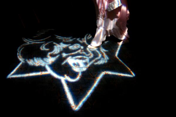 The face of Suzi Bass is projected on the floor.