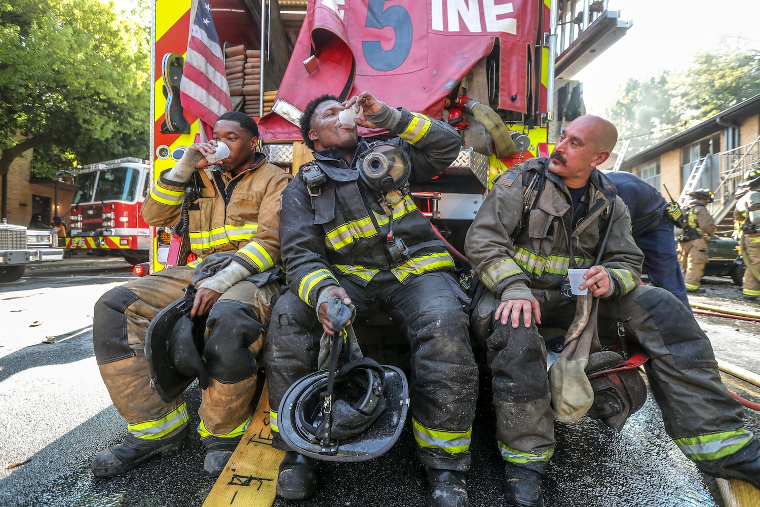 July 7, 2022 Atlanta: Atlanta Firefighters (Left to Right) Bernard Benn, Joshua Bell and Jonathan Oliver of Engine 5 rehab from the heat as Atlanta firefighters had a hot morning battling an apartment blaze in the 2200 block of Campbellton Road in Atlanta on Thursday, July 7, 2022. The call came in at 9 am for the Adams House Apartments where units arrived to heavy smoke conditions according to Atlanta Fire Rescue Captain Taurus Durrah. Flames erupted from the bottom floor to the top floor and then the attic Durrah said. Crews initially had to bring in tank water to get water on the fire because of the 800 foot distance to the hydrant on Campbellton Road. Four units were damaged and 8-families displaced. No one was injured and the fire is under investigation. Durrah said more units are being sent to fire scene to shorten the rotation of fire crews due to the heat. Firefighters are told to hydrate  and stay cool a full shift before coming to work to combat the heat. (John Spink / John.Spink@ajc.com)


