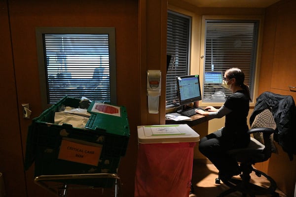 Registered nurse Kari Ruis works on a computer as she monitors her patient at the Intensive Care Unit. This past year during the pandemic, she took up long distance running to help fight the stress from the job. She sometimes runs with her colleagues. She recently ran a half-marathon. "It's just a good way to go and get it all out, my frustration and put it into exercise and running," she said. (Hyosub Shin / Hyosub.Shin@ajc.com)