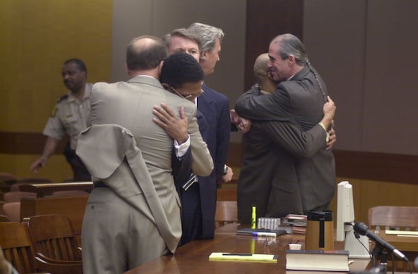 Defense attorney Steve Sadow, far left back to camera, hugs his client, Joseph Sweeting, after not guilty verdicts were announced for both defendants in the Buckhead double murder trial in Fulton Superior Court in 2000. (Kimberly Smith/AJC file)