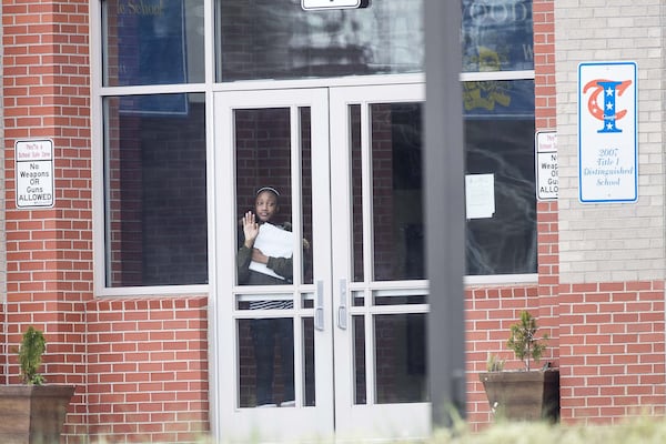 A student waits at the front entrance at Woodland Middle School in East Point, Monday, March 9, 2020. The Fulton County School system has decided to close schools on Tuesday after a teacher tested positive with the coronavirus. ALYSSA POINTER/ALYSSA.POINTER@AJC.COM